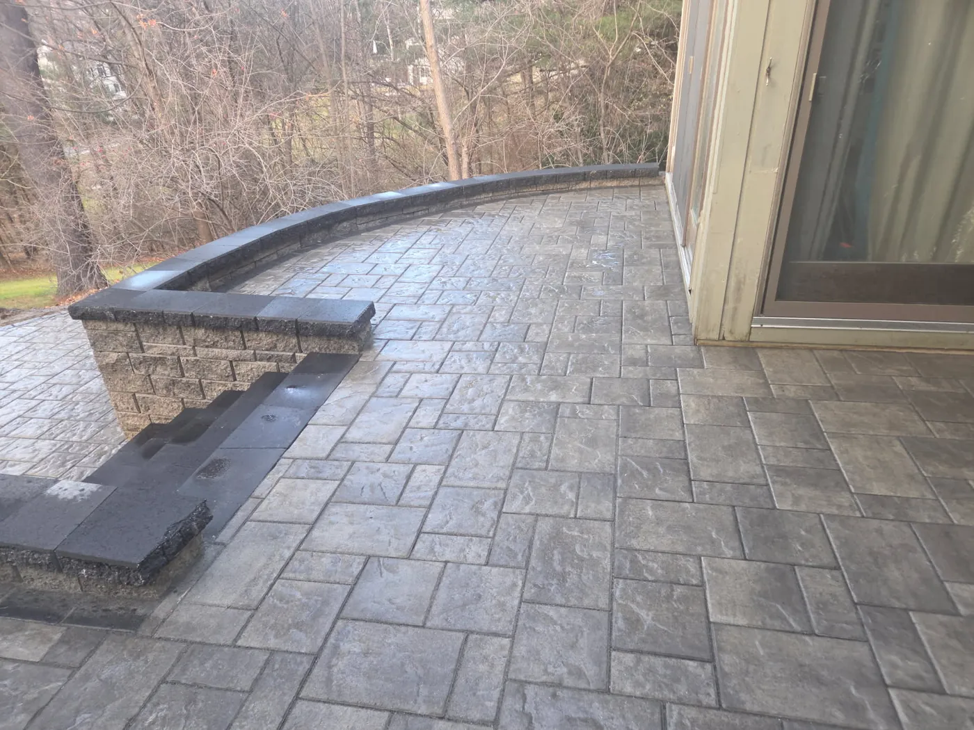 Stamped slate pattern patio with a curved block seat wall by a sliding door